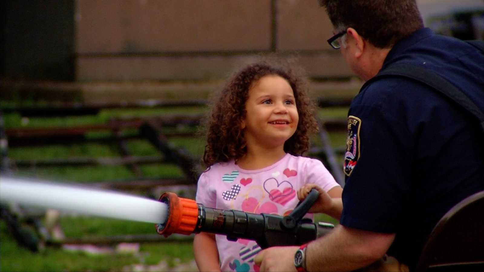 A girl tries out a fire hose with help from a Golden Valley firefighter at the Public Safety Open House