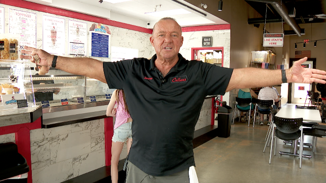 man standing in an ice cream shop with his arms extended