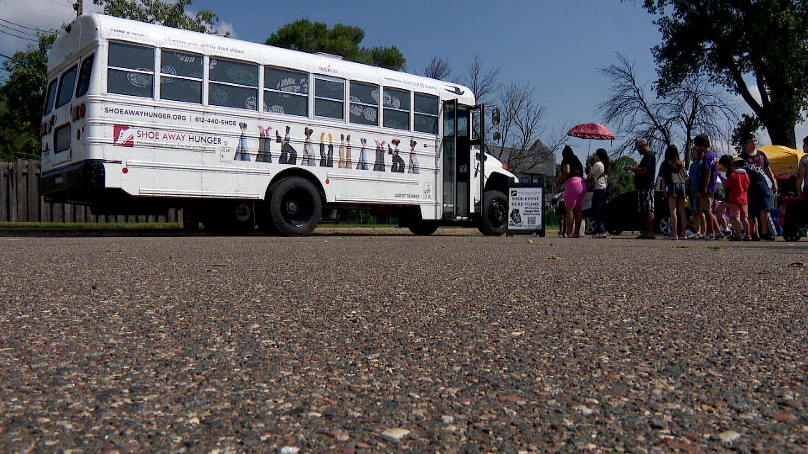 White bus decorated with shoe decal, line out the door
