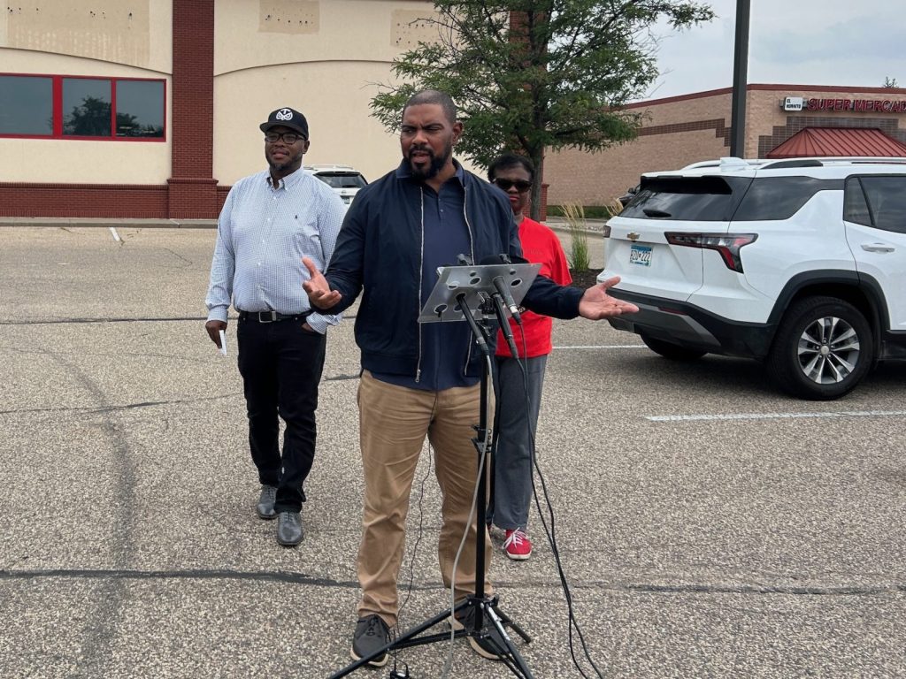 people standing at a podium in the middle of a parking lot