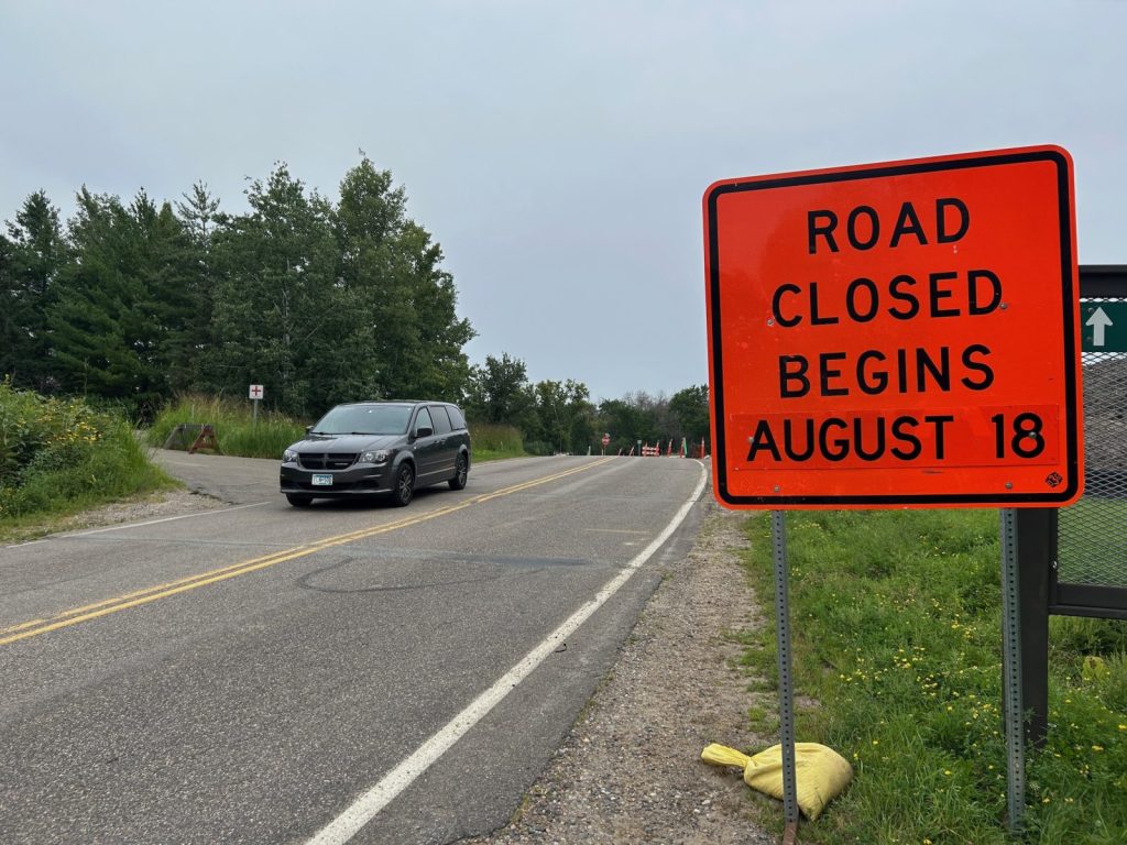 car drives past a sign warning people of a road closure