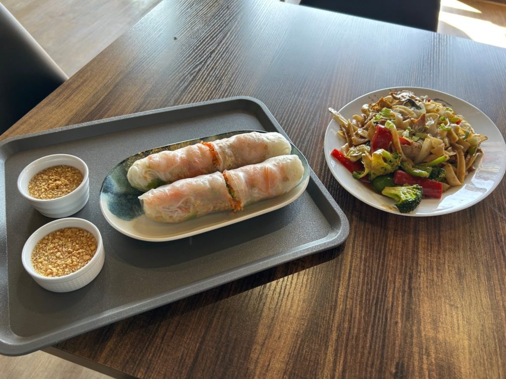 spring rolls and drunken noodles sitting on a table