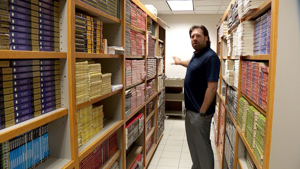 English teacher stands between two stocked book shelves