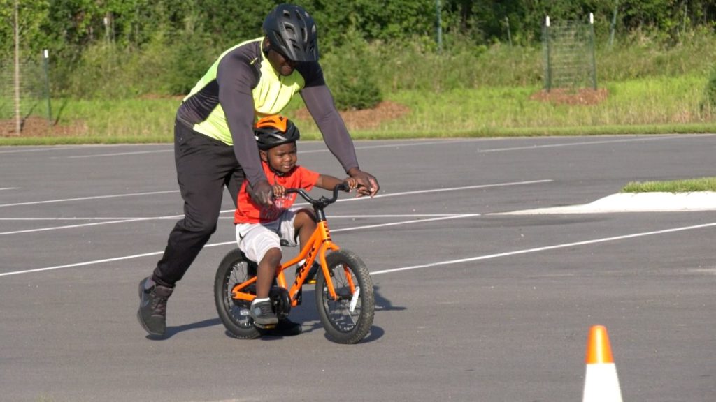 Adult helps a child ride a bike