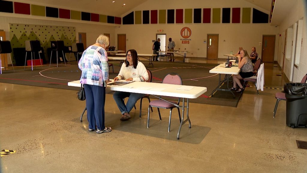woman checks in to vote at a white folding table