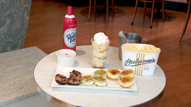 cupcakes, ice cream and whipped cream sitting on a table at nadia cakes