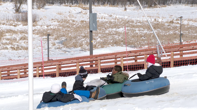 people going down a tubing hill in the winter