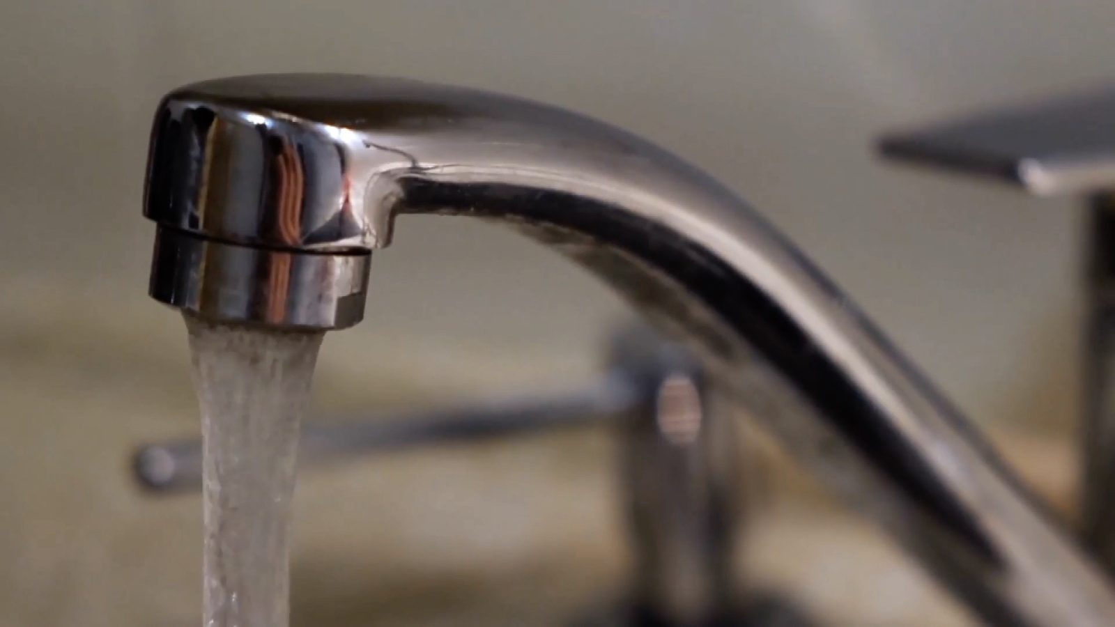 tight shot of water coming out of a faucet of a kitchen sink