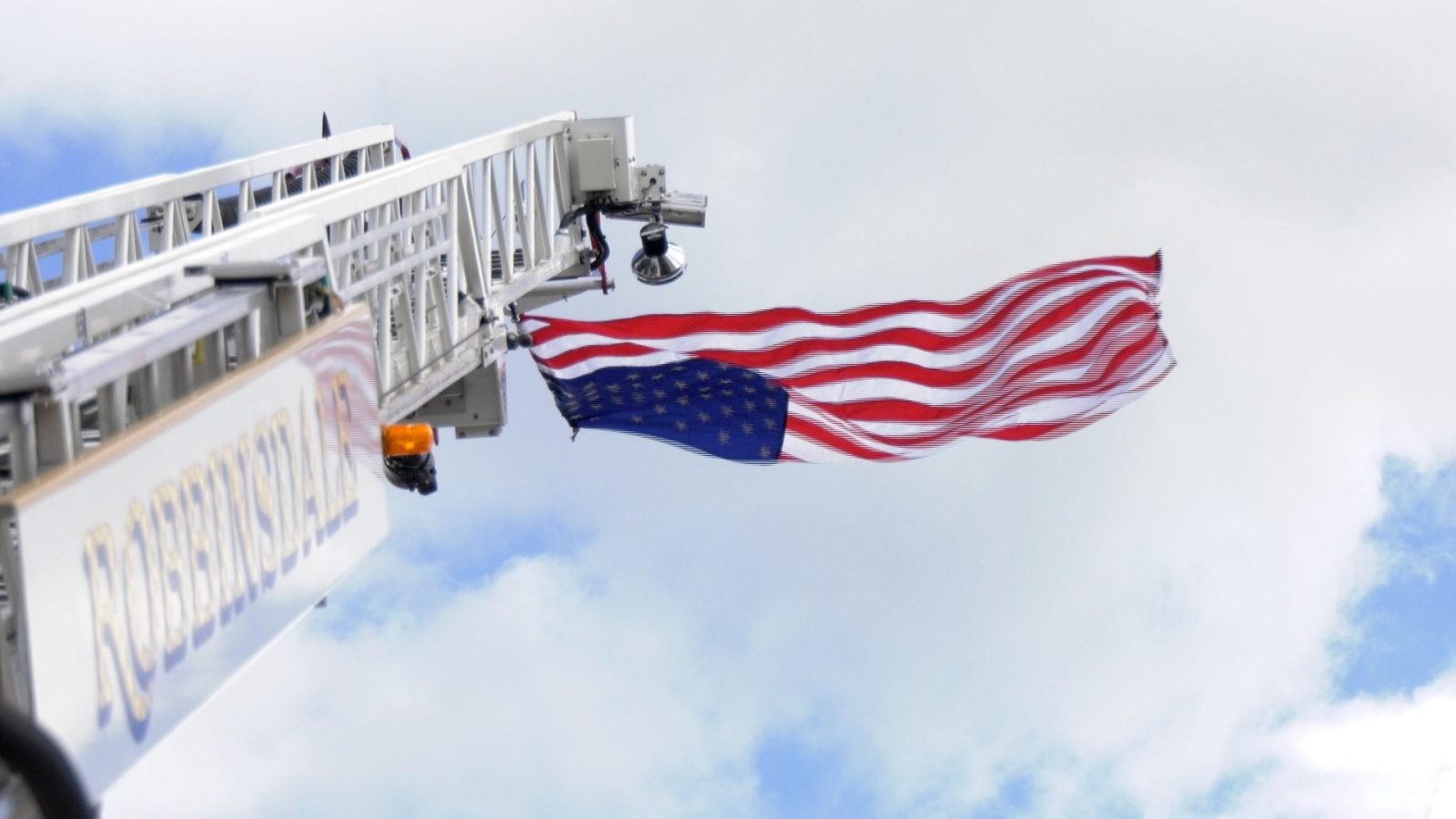 American flag waves as its flown from the top of an aerial platform of a Robbinsdale Fire Dept truck