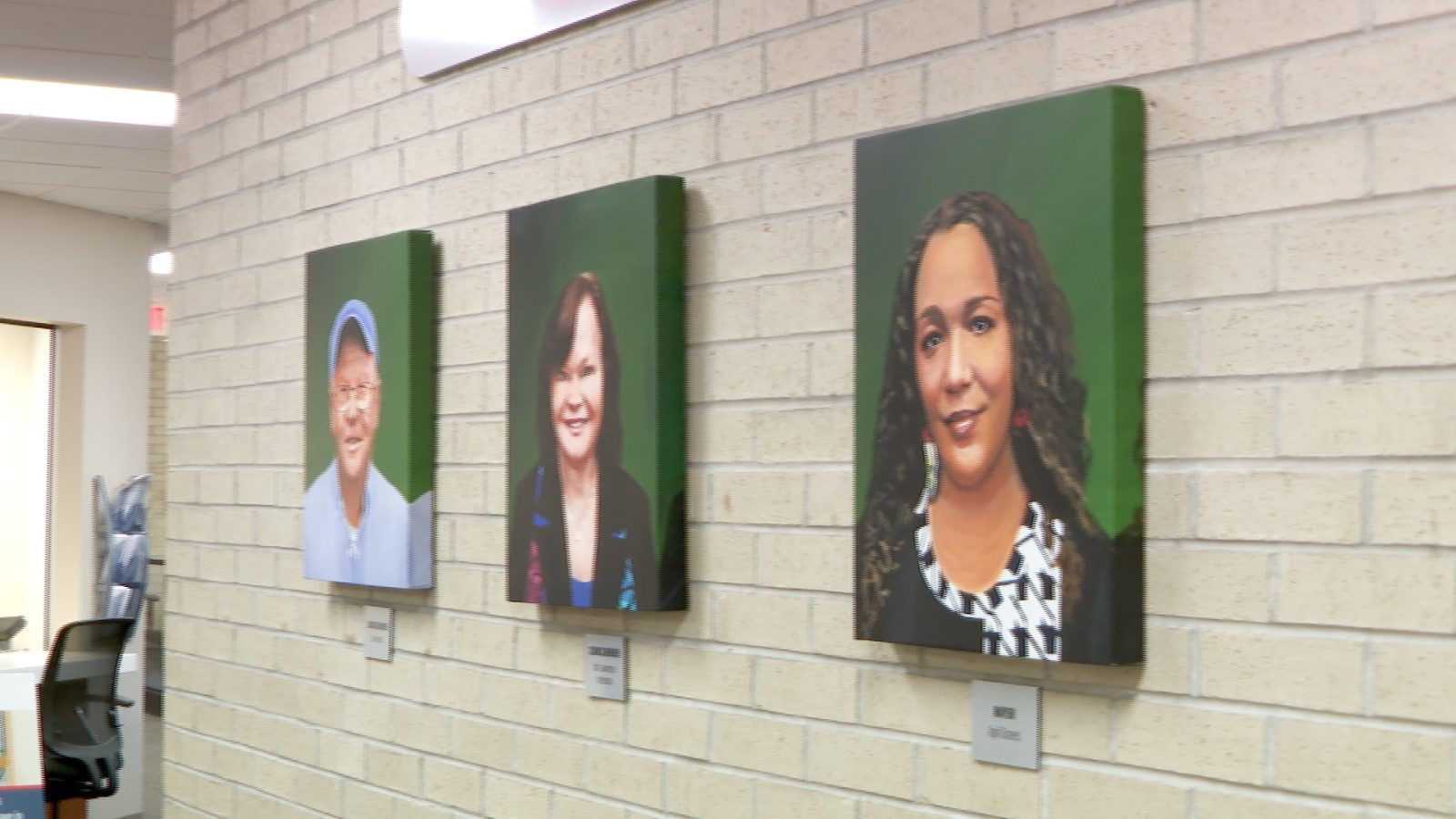 portraits hang on a wall inside city hall