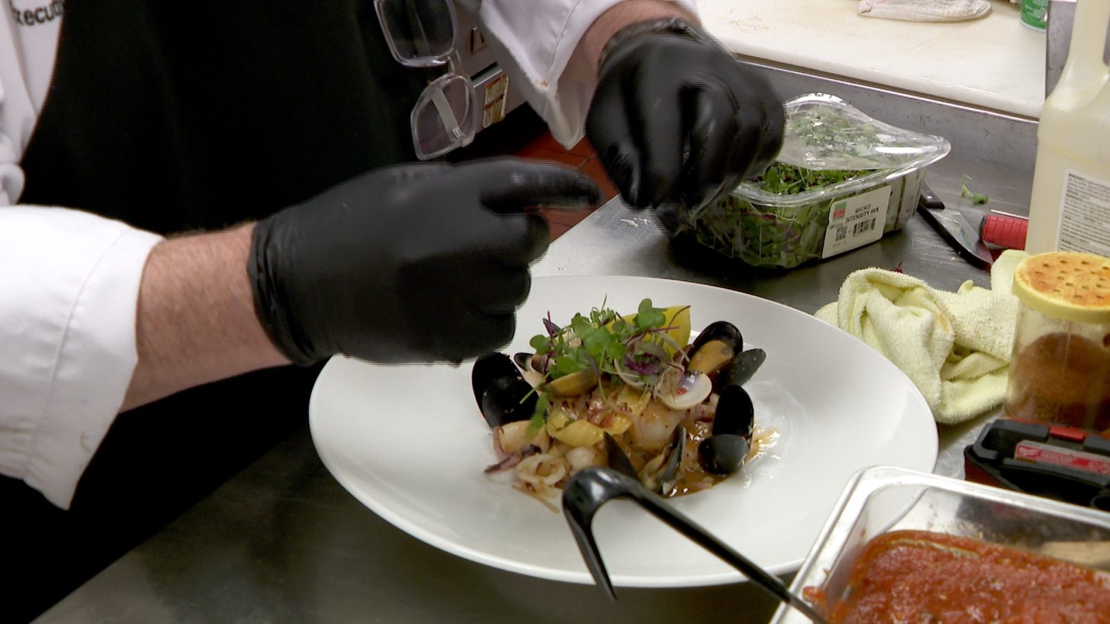 chef prepares a plate of pasta and seafood in a restaurant kitchen