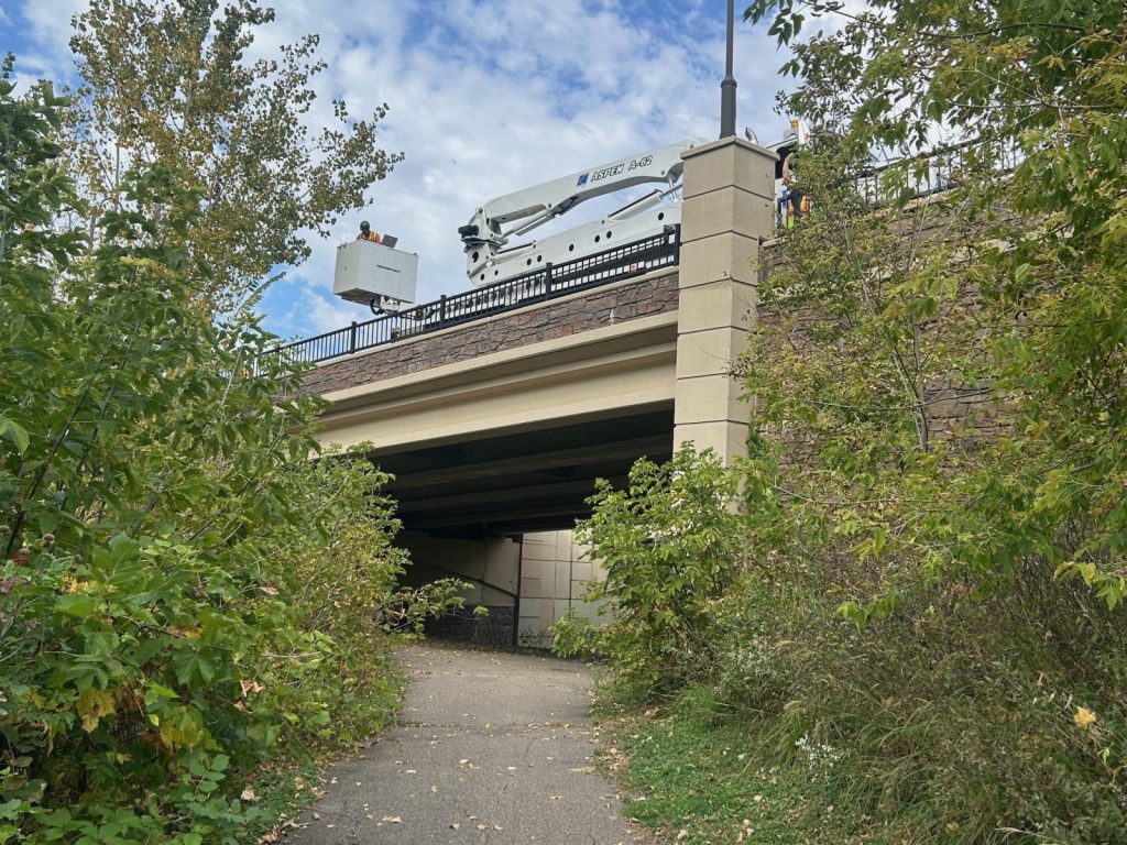 a bridge surrounded by trees with an Under Bridge Inspection Vehicle atop the bridge