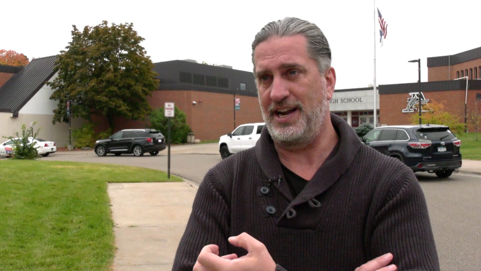 man speaking in front of a school building