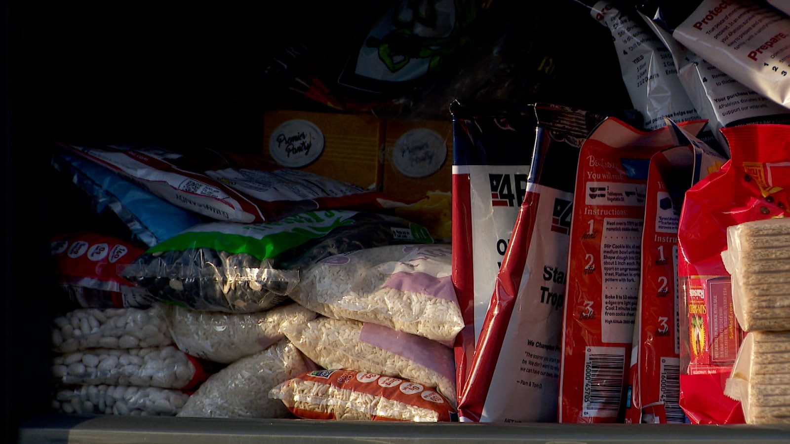 A cupboard shelf stocked with food, including pantries, instant meals and rice