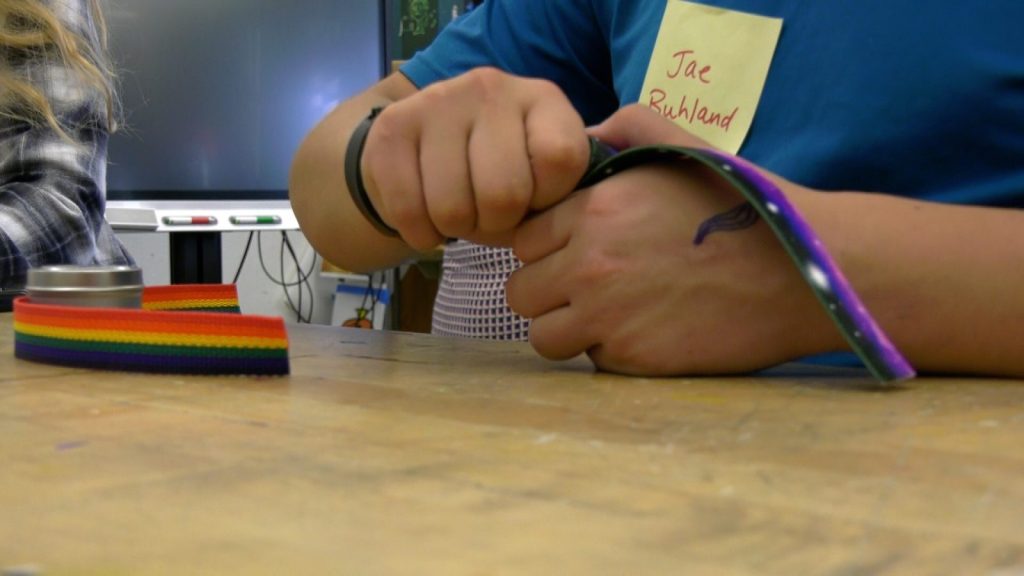 Hands of a student rolling up a galaxy-patterned piece of ribbon