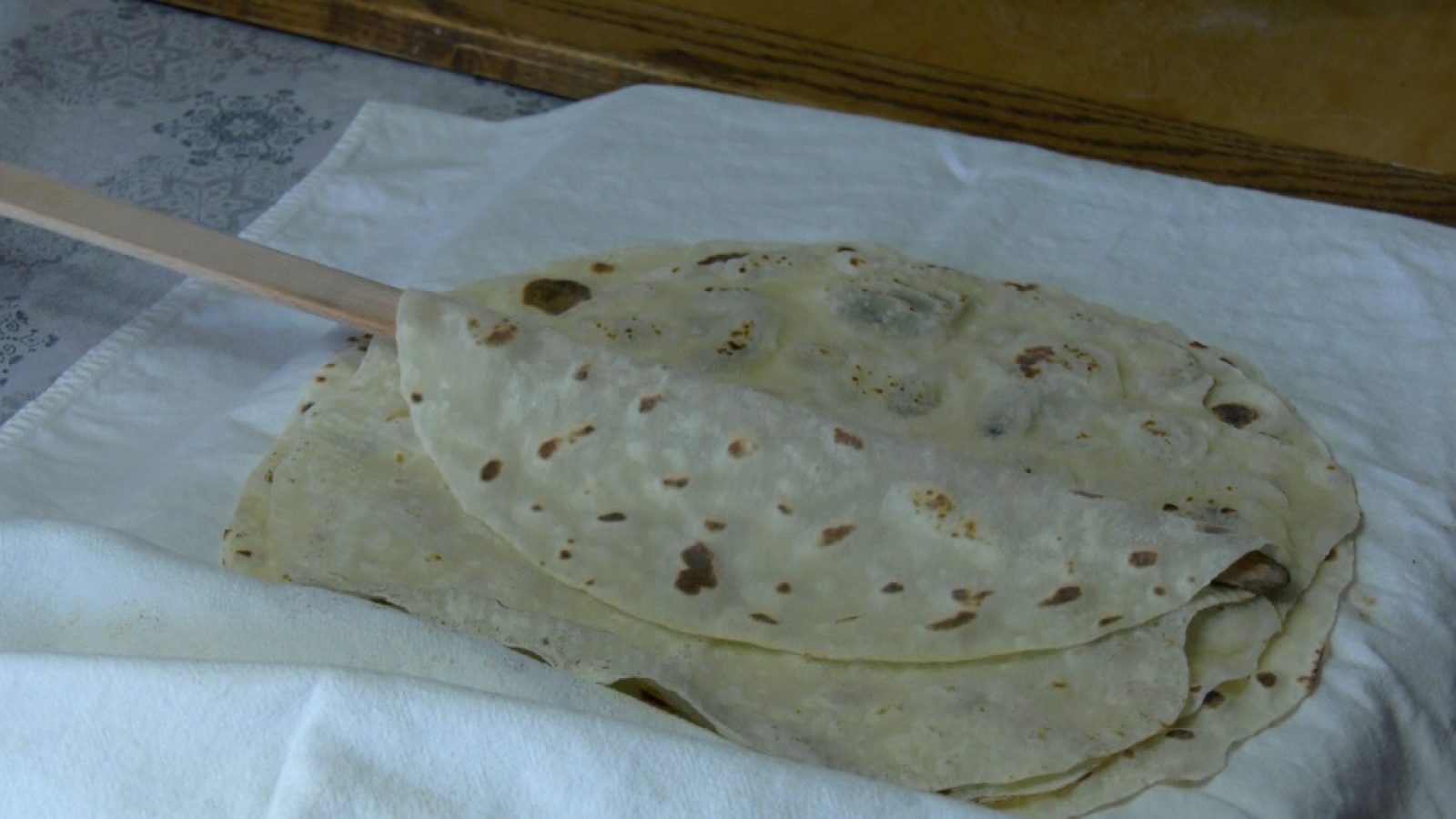 lefse being stacked between cloths using a turning stick