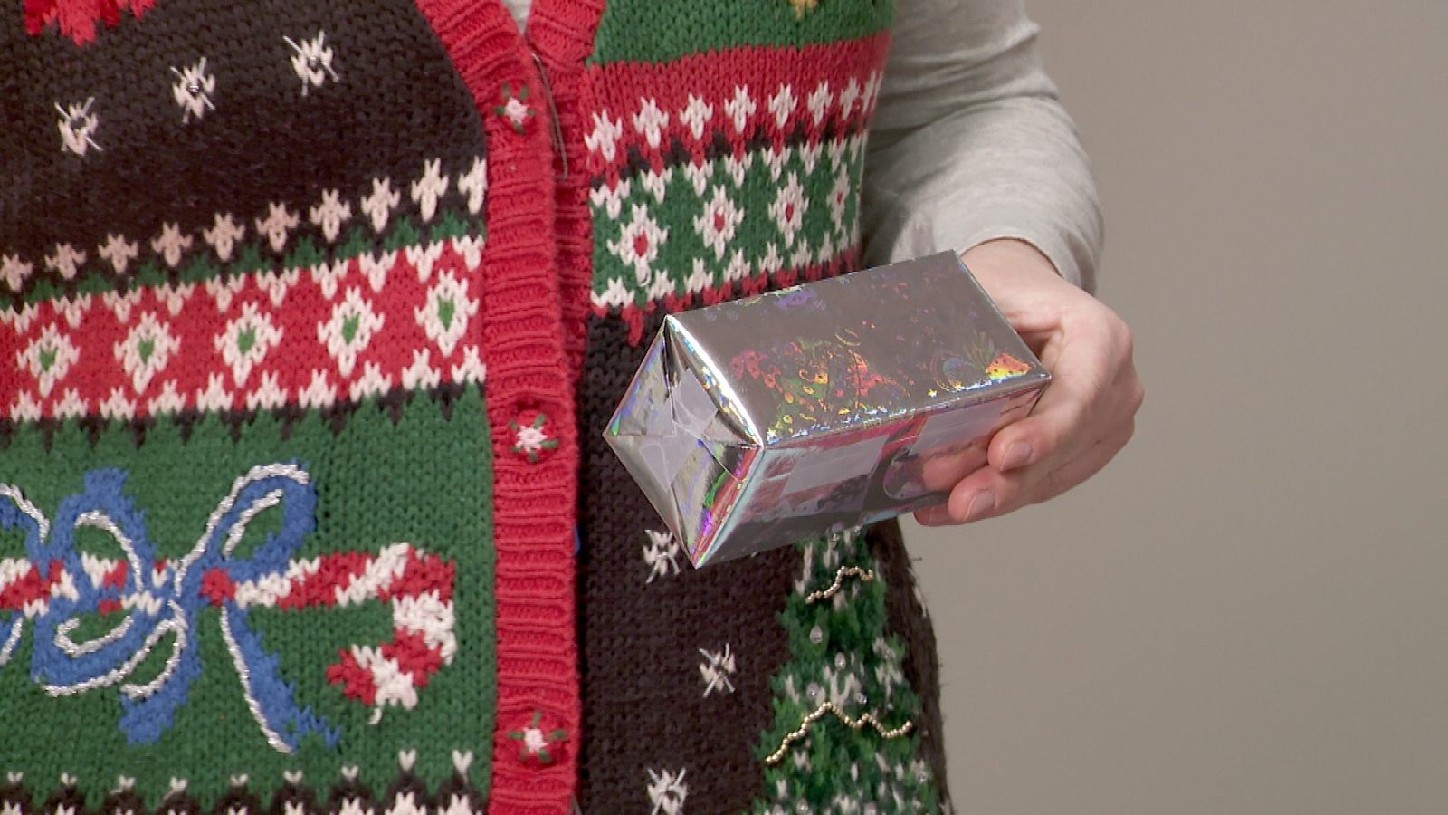 A woman holds a small gift wrapped box.