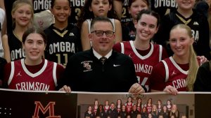 Maple Grove head girls basketball coach Mark Cook holds up a banner recognizing his 400th career win at Maple Grove