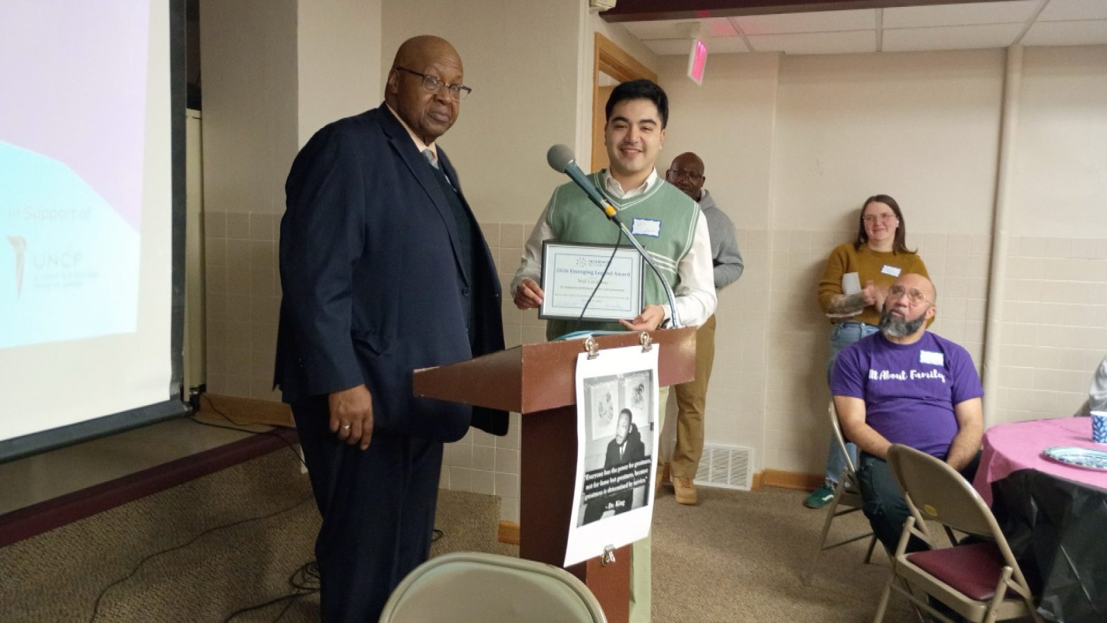 Man receiving certificate of commendation at a breakfast meeting