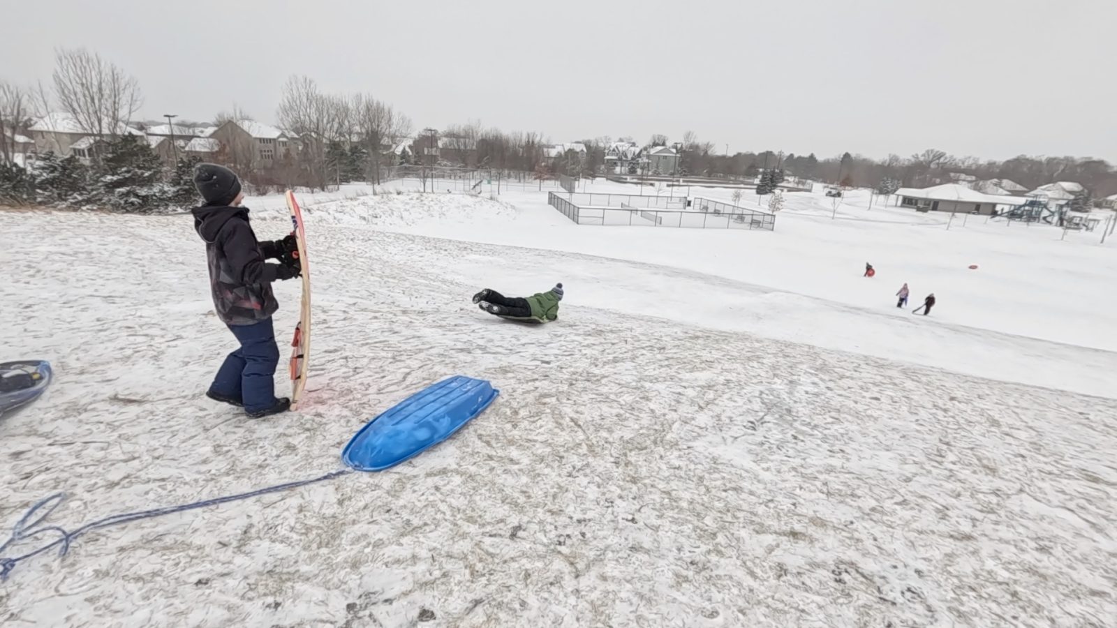 children sledding down a hill on a winter day