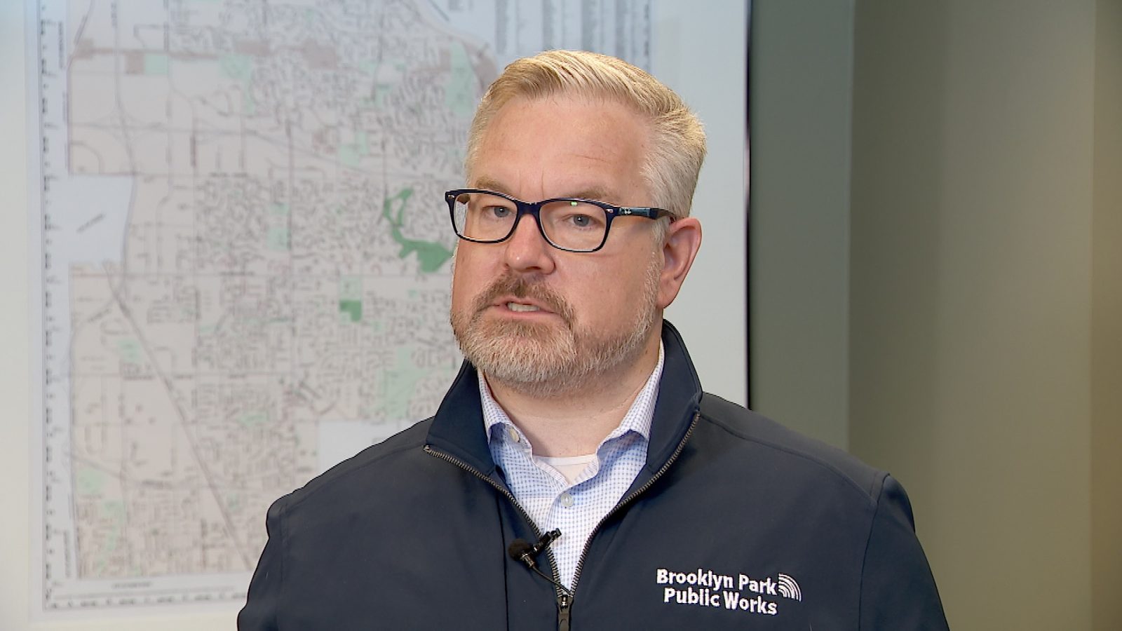 Man interviewed on television in front of a city map on the wall