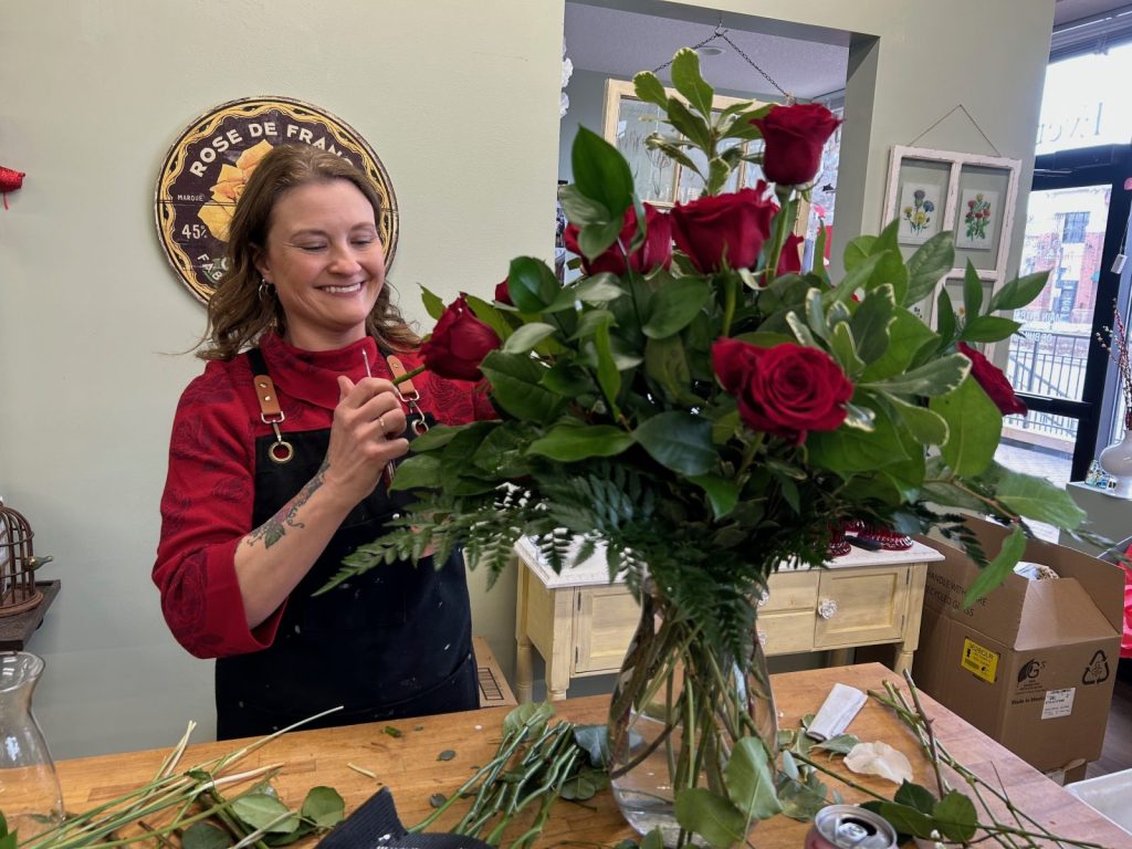 woman arranges a bouquet of red roses at Styled Stem flower shop