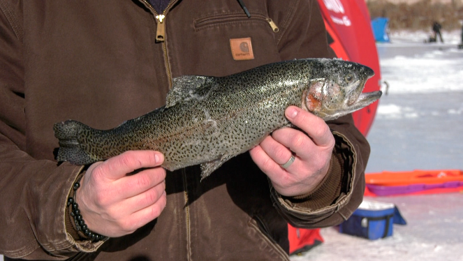 man holding a fish on a frozen lake