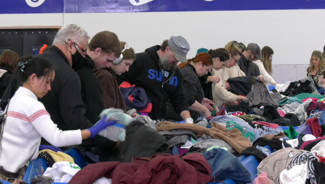people rummaging through clothes at a goodwill store
