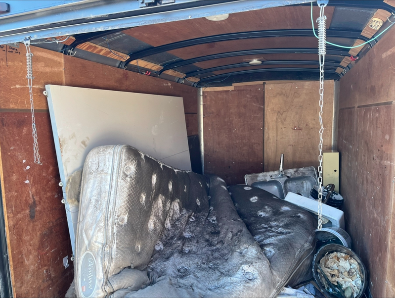 inside of a trailer with a dirty mattress and other various things