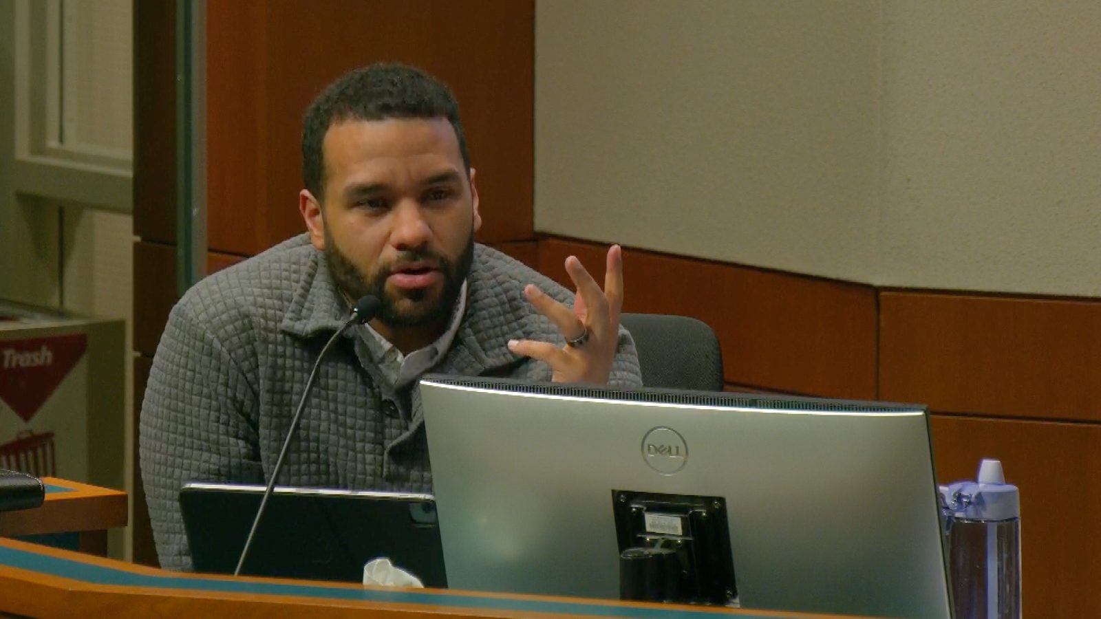 man speaks into a microphone during a city council meeting