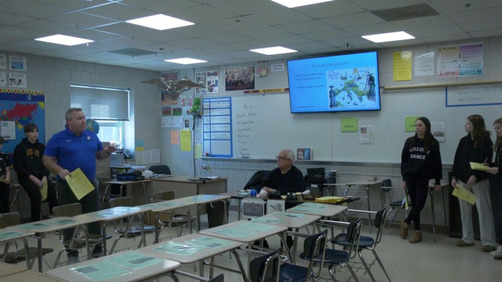 teacher talking to students with desks organized in the middle