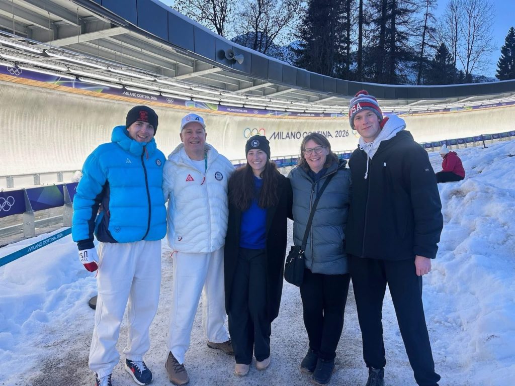 five people, including rich ruohonen, stand in front of a track at the olympics