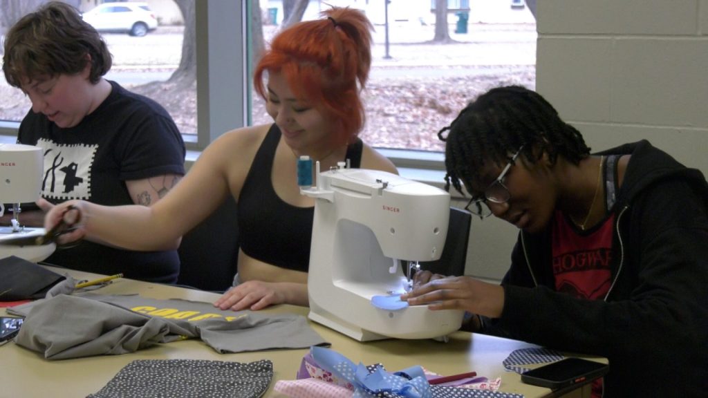 three people work at sewing machines