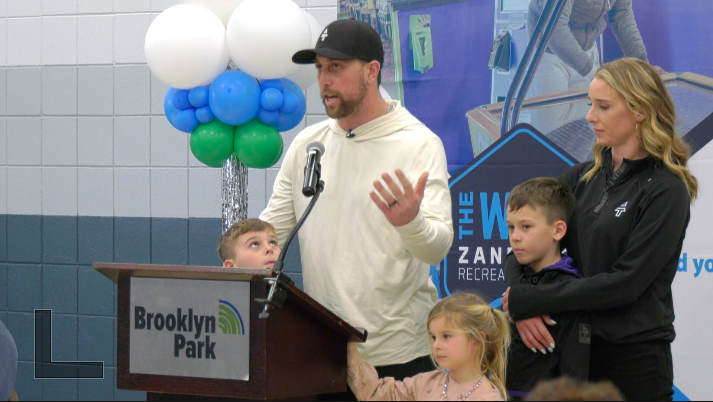 adam thielen and his family speak at a podium in Brooklyn Park
