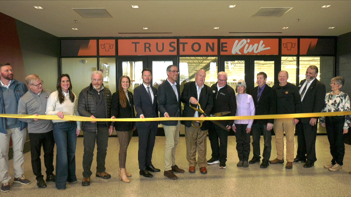 people getting ready to cut a ribbon in front of a sign that says Trustone Rink