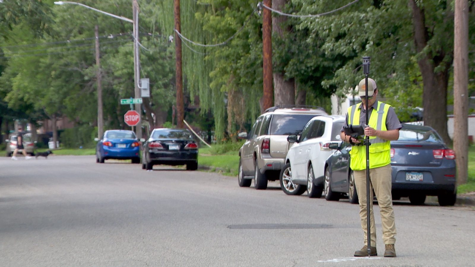 man uses survey equipment to take measurements on a neighborhood street