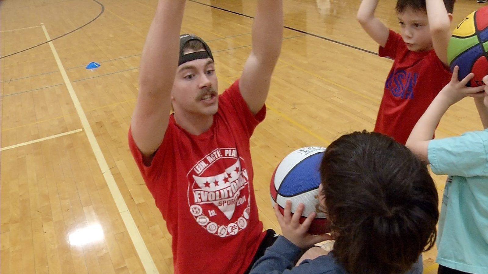 man coaches little kids in basketball