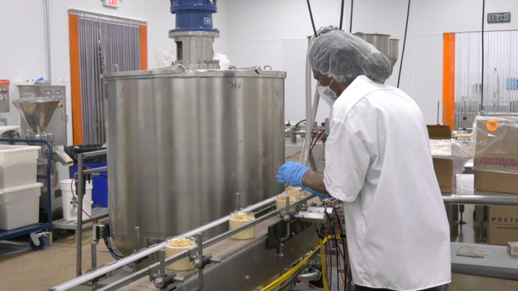 employee at Fit Butters scooping a topping on