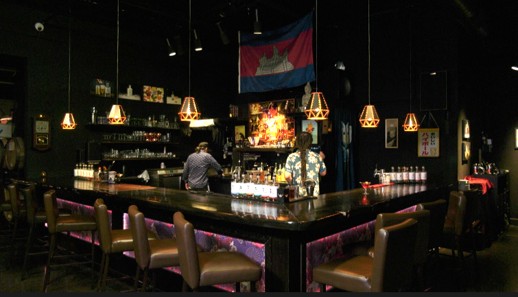 the bar at skaalvenn distillery in brooklyn park, with a cambodian flag hanging on the wall