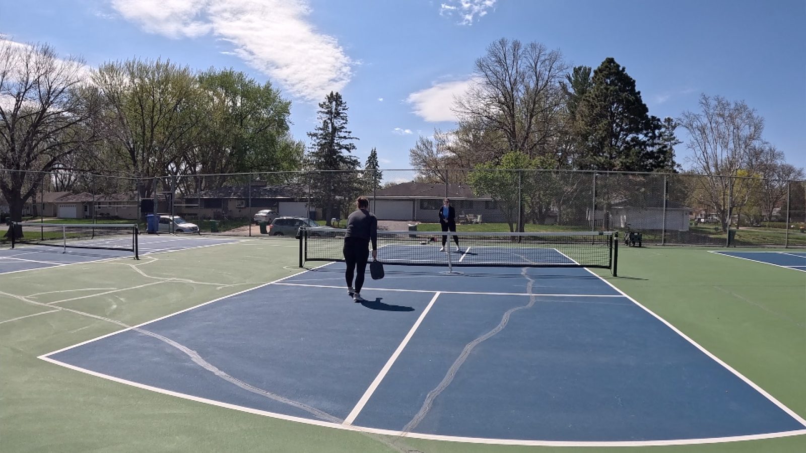 two women play pickleball on an outdoor court