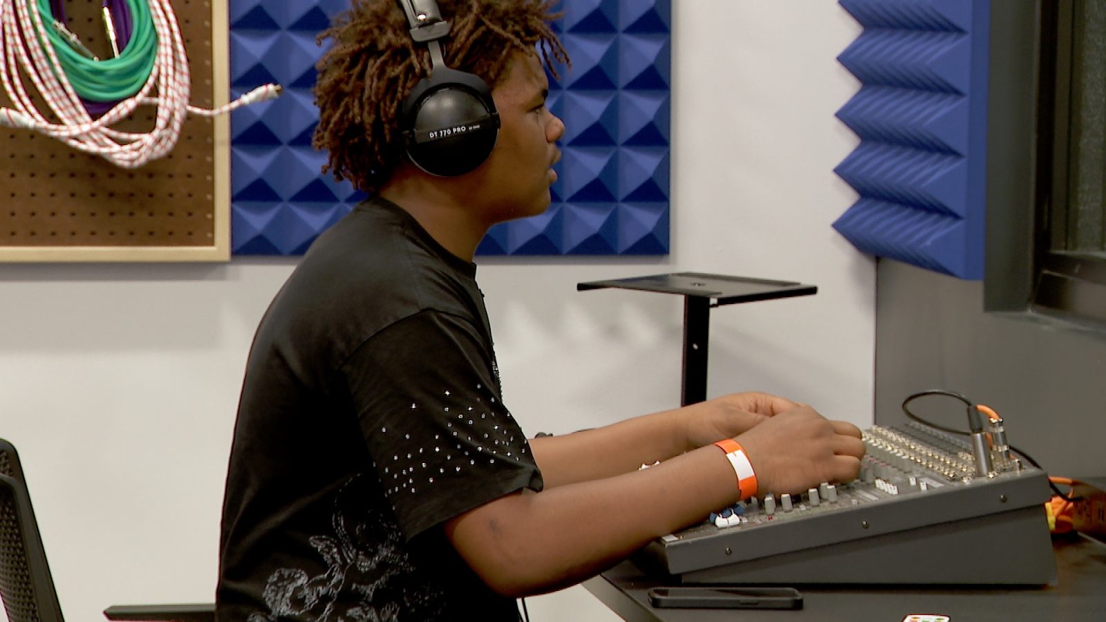 teenaged boy works a sound board in a recording studio