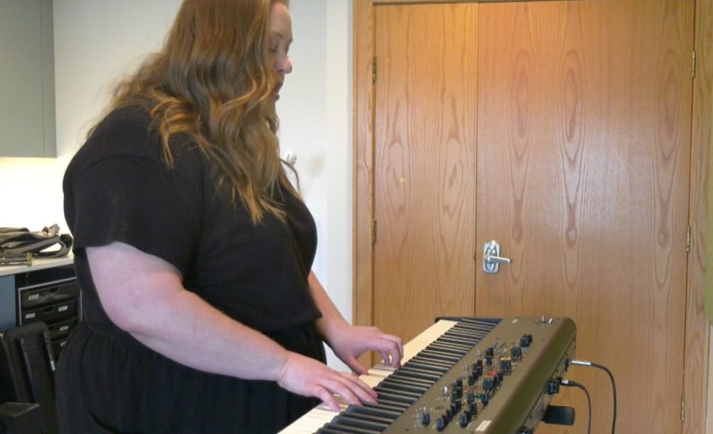 red-haired woman playing keyboard insdoors
