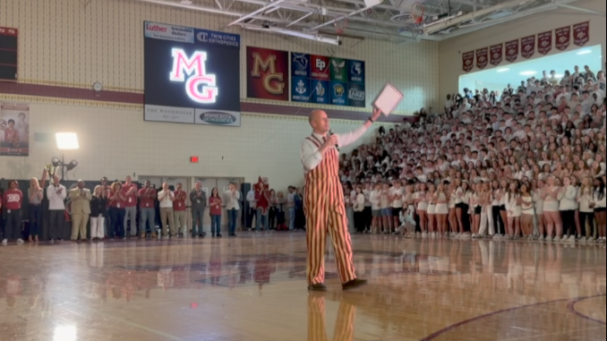 bart becker holds up his principal of the year award at Maple Grove Senior High pep rally