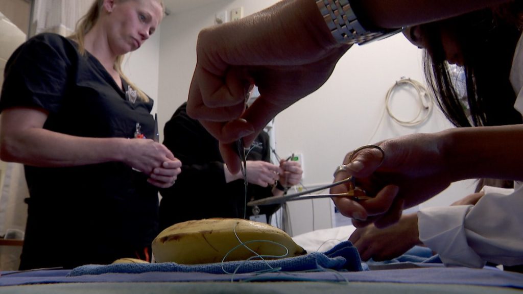 a banana with a needle and scissors, nurses in the background