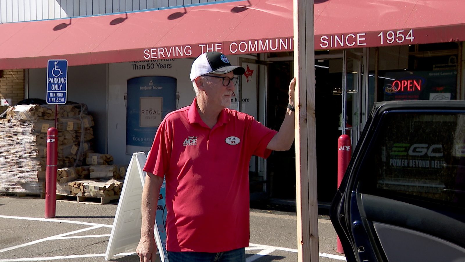 man holds piece of lumber outside a hardware store