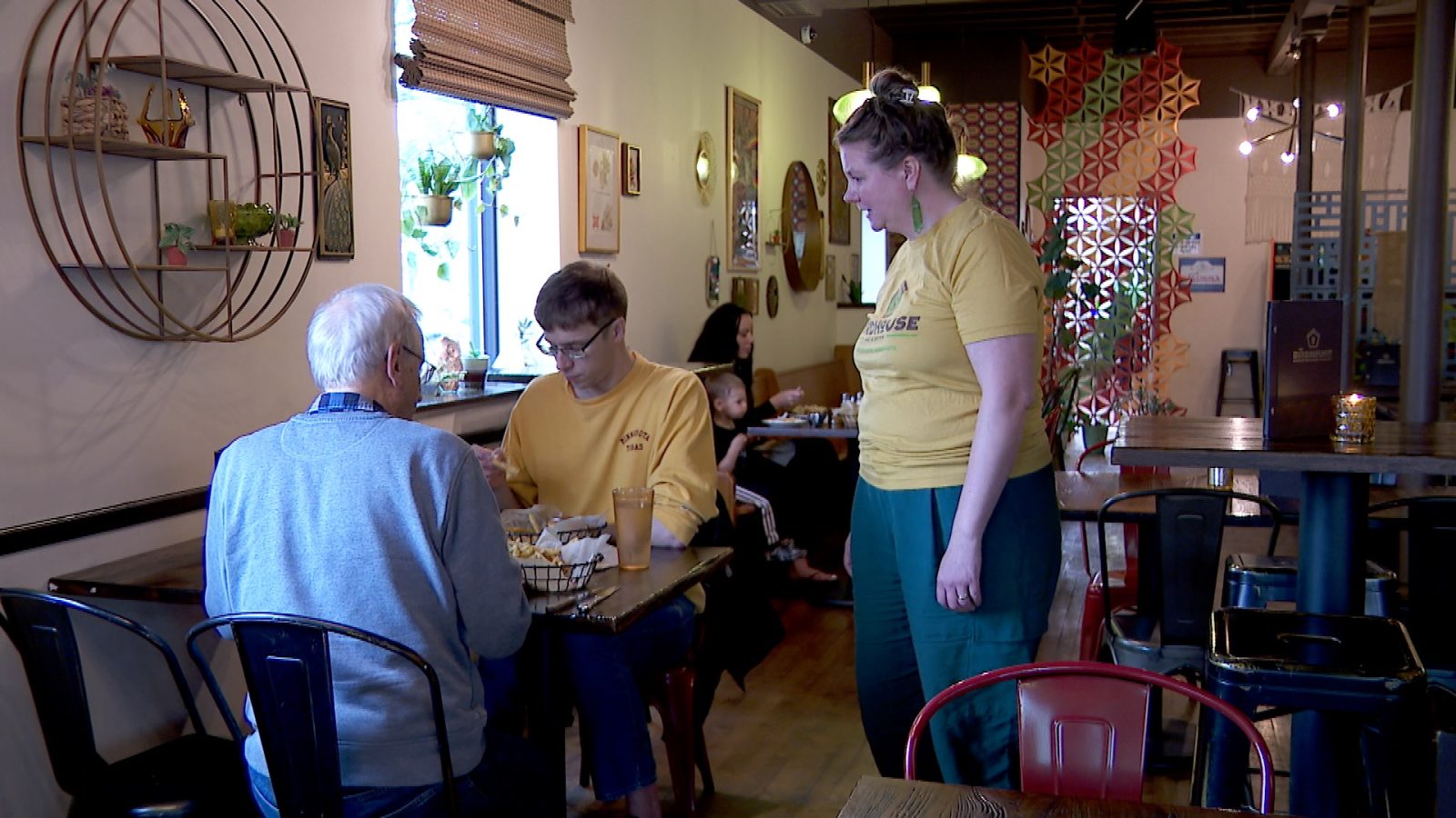 Two diners in a restaurant speak to their server at their table