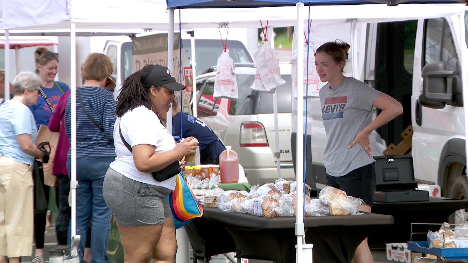 shoppers browse items at an outdoor farmers market