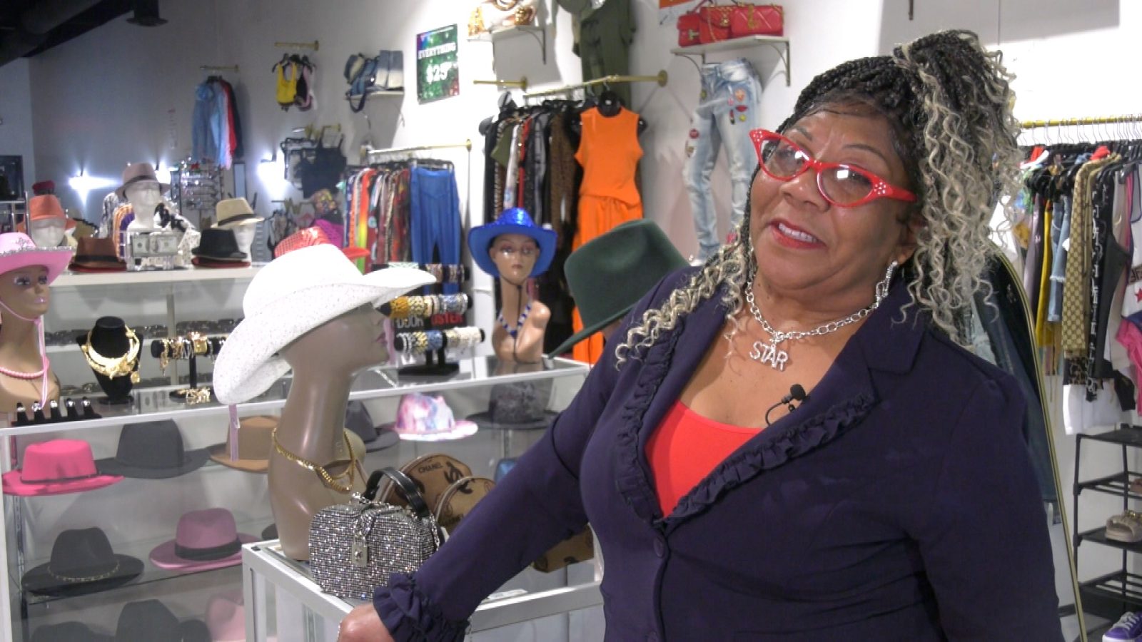 Betty Sanders standing in her store, she's wearing red glasses and a blue blazer