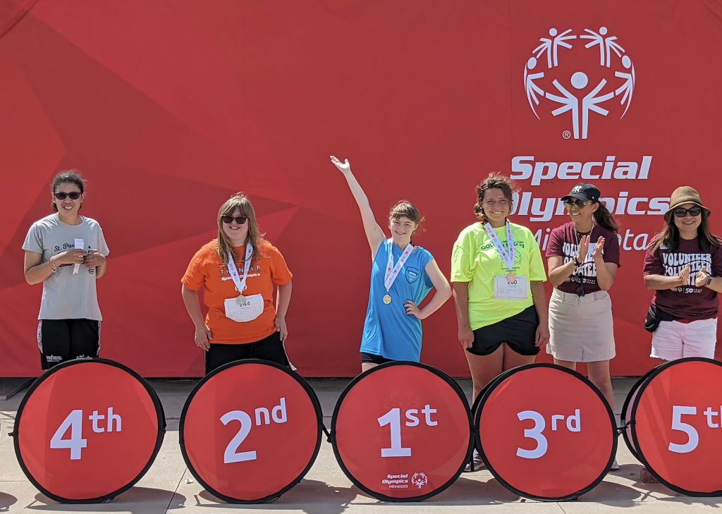 elizabeth standing behind a first-place circle at a special olympics event