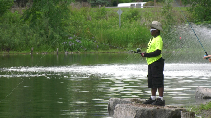 a kid fishing in brooklyn park during the annual cops n kids fishing event